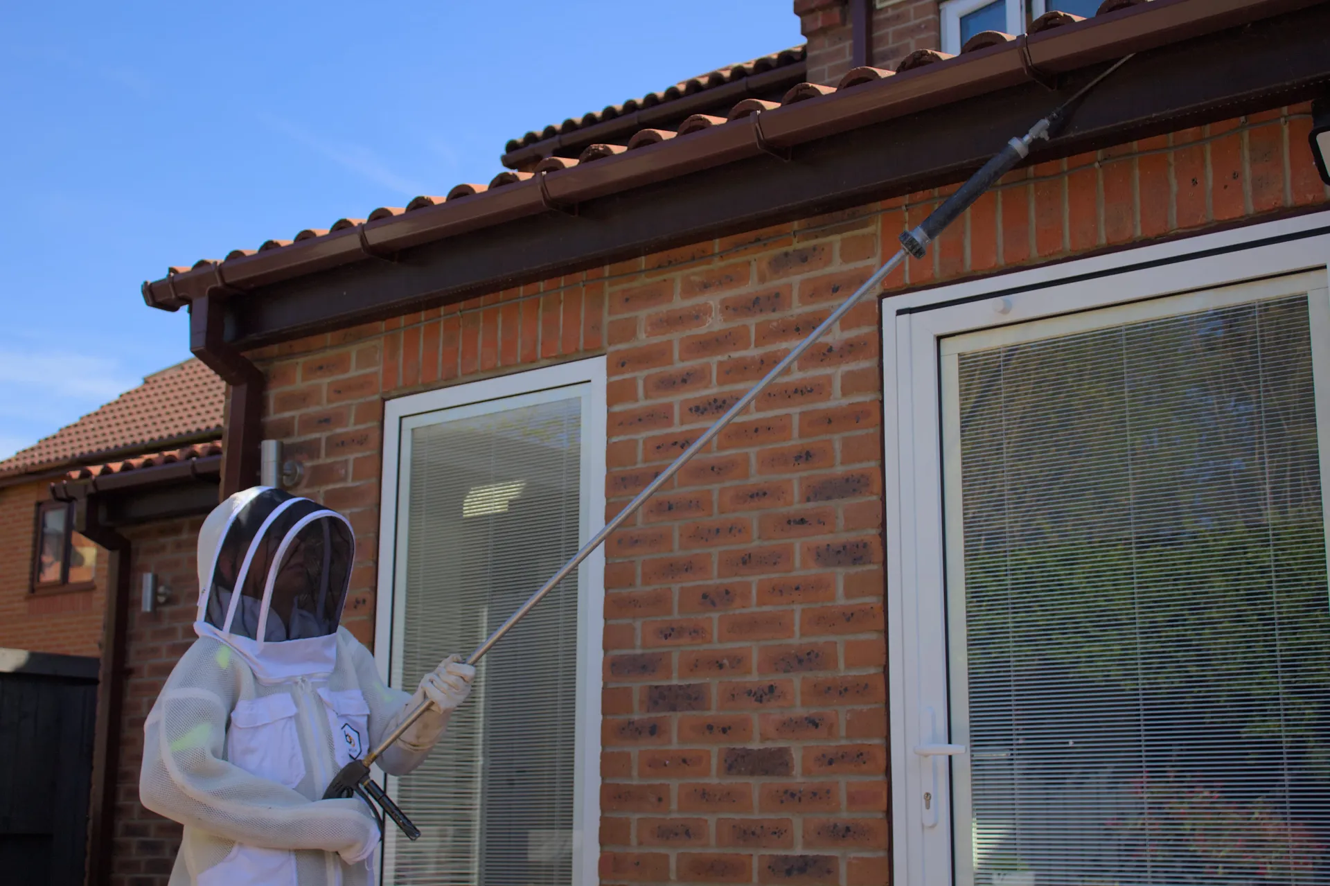 Professional wasp nest removal in Harrogate being performed by a technician in a protective suit using specialized equipment.